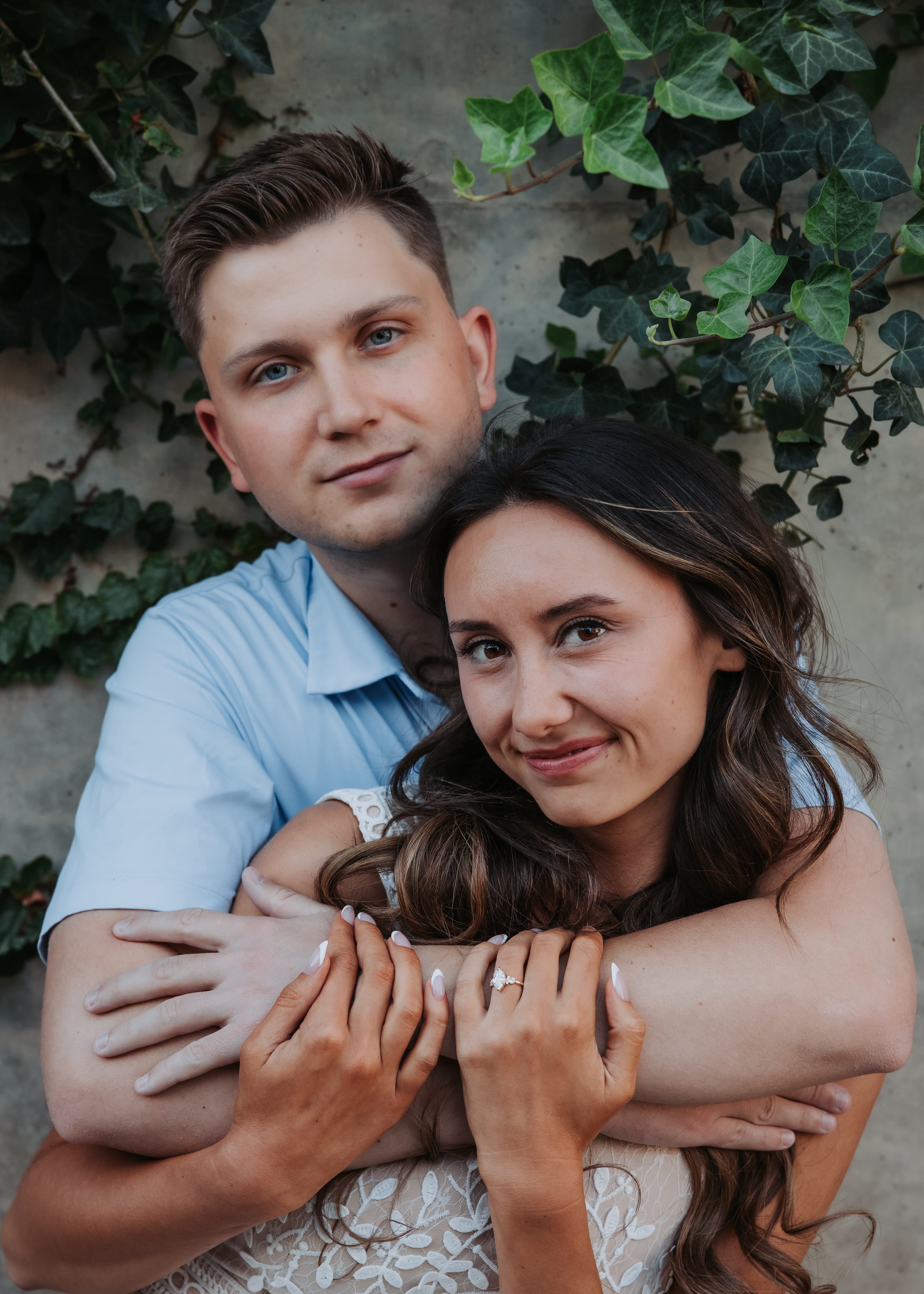 Bronson embracing Bre beside an ivy-covered wall